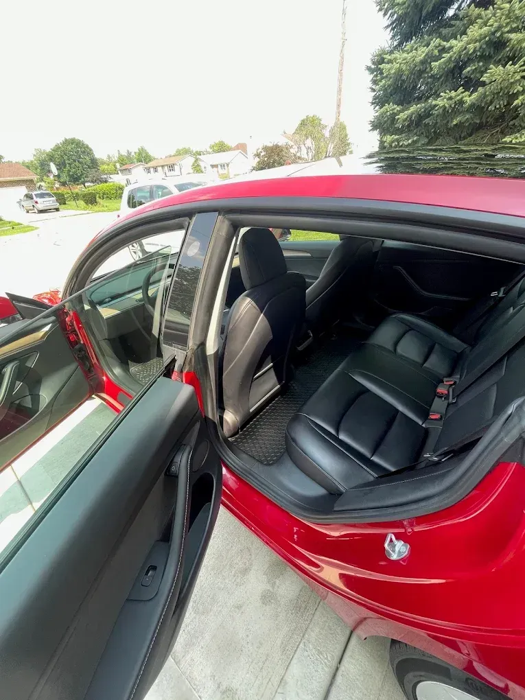 Open red car with black leather seats and driver door open outside on a driveway