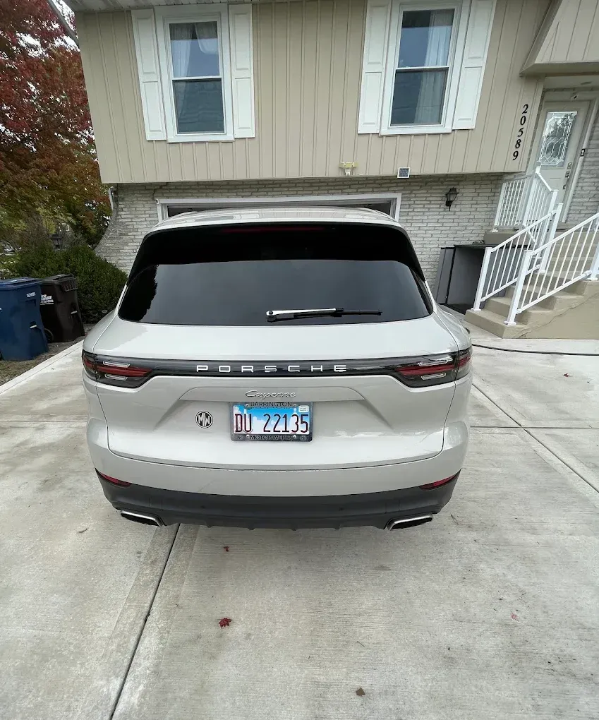 Rear view of a beige SUV parked in a driveway in front of a house