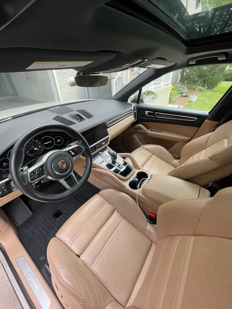 Beige luxury car interior with steering wheel, dashboard, center console, and front seats