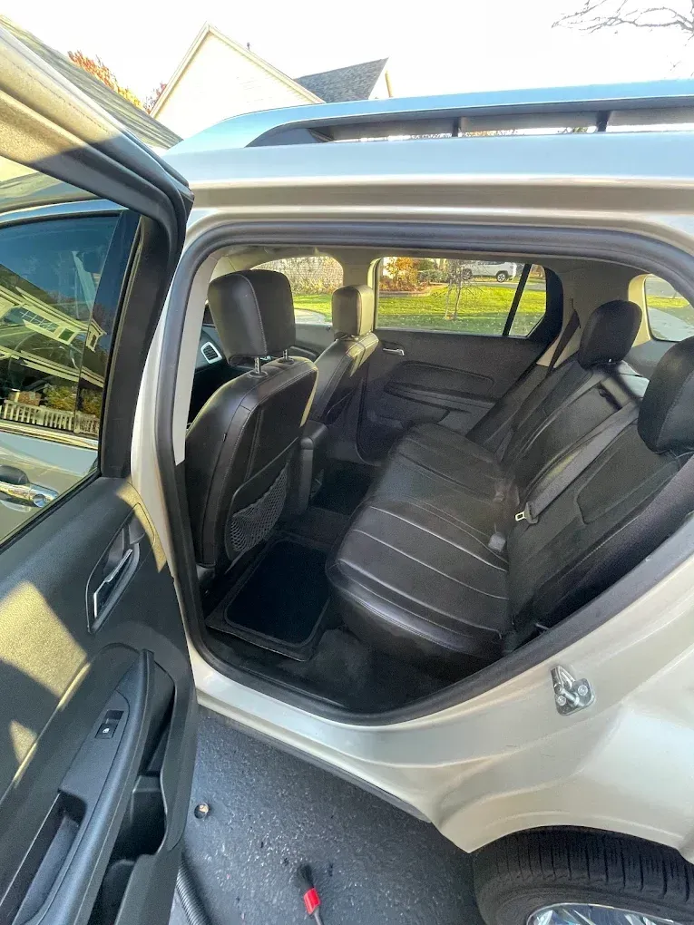 Open car door showing black leather rear seats and beige interior