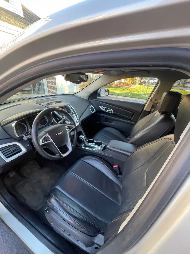 Black leather car interior viewed from the open driver's door, showing front seats and dashboard.