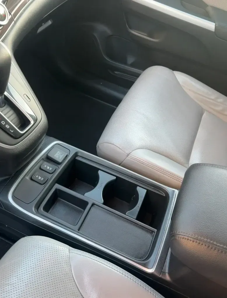 Car interior with gray seats and a center console cup holder and storage tray