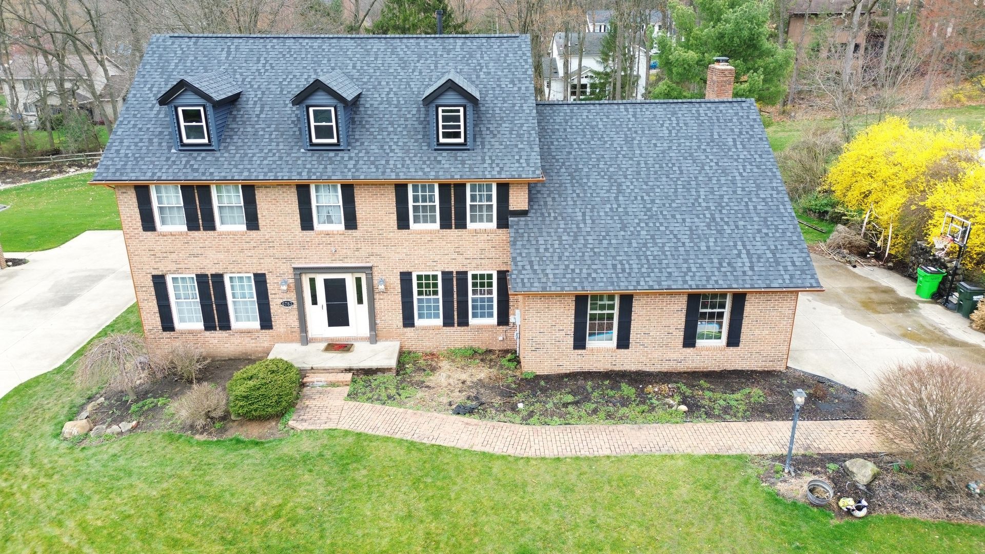 An aerial view of a large brick house with a blue roof.