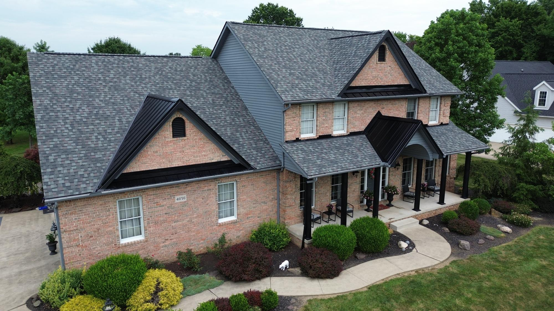 An aerial view of a large brick house with a gray roof.