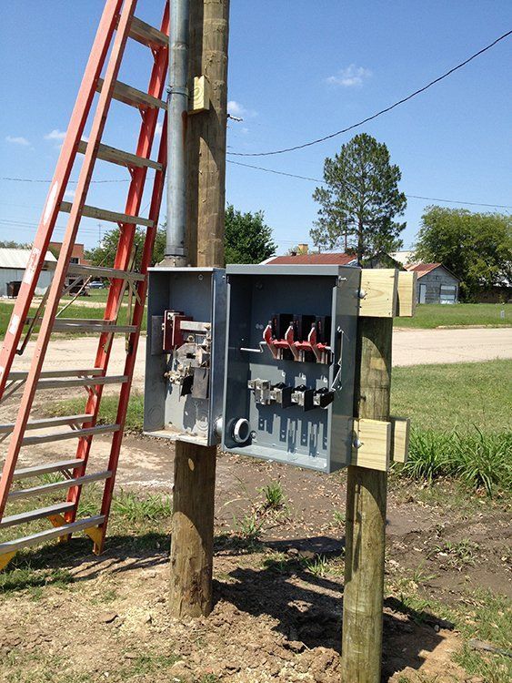 a ladder is sitting next to a box on a pole .