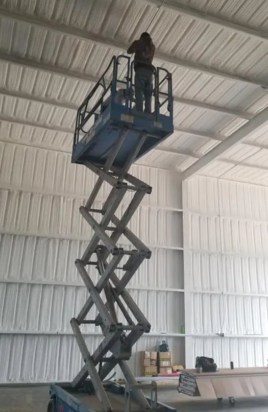 a man is standing on a scissor lift in a warehouse .