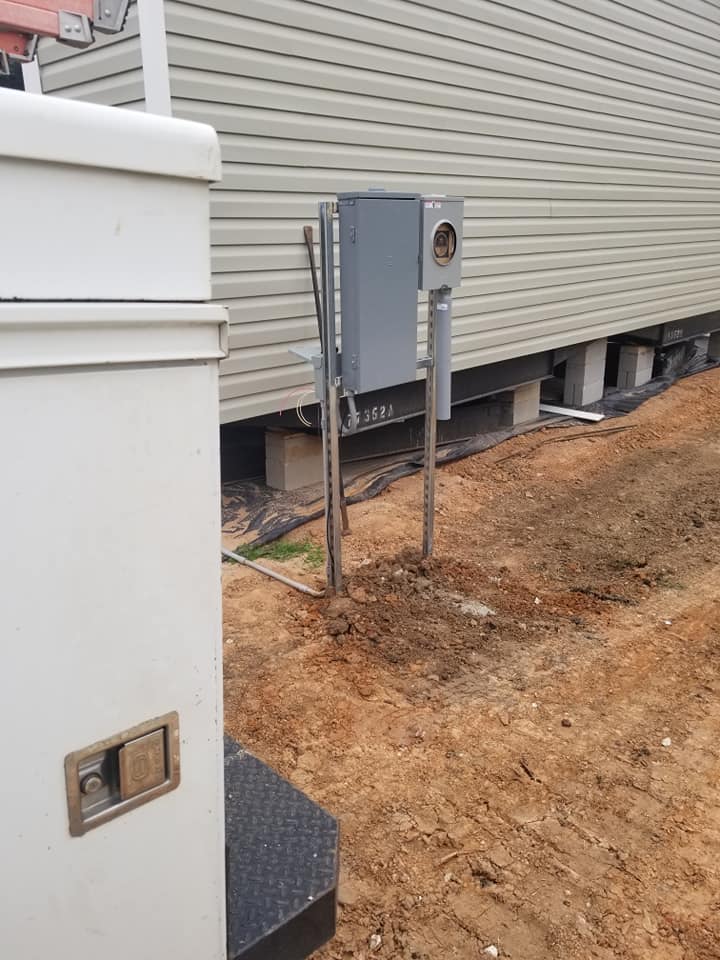 a electric and meter box is sitting in the dirt next to a house .