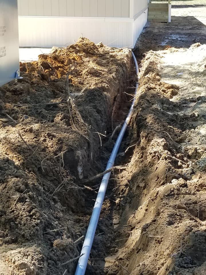 a pipe is being installed in the dirt next to a house .