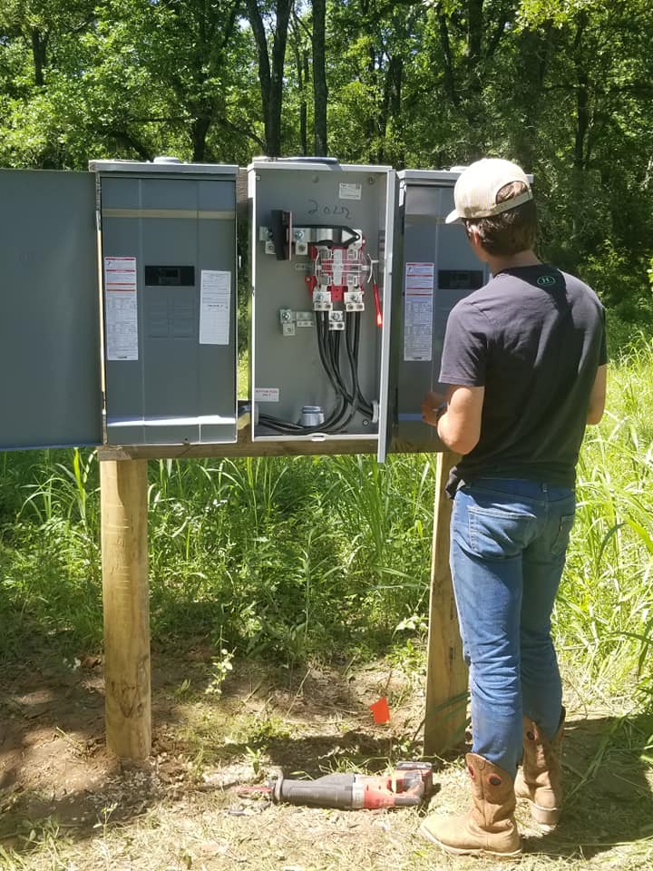 a man is standing in front of a electrical box in the woods .