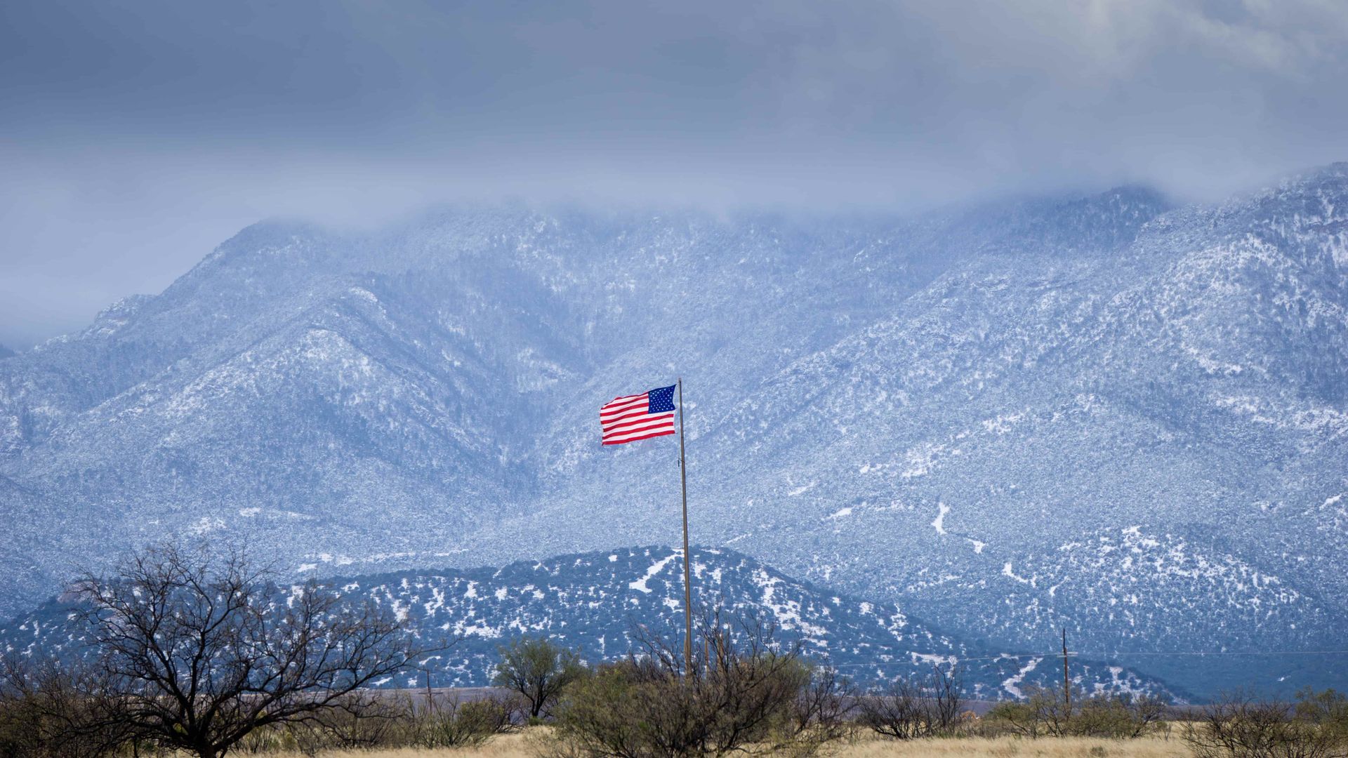 An american flag is flying in front of a snowy mountain.