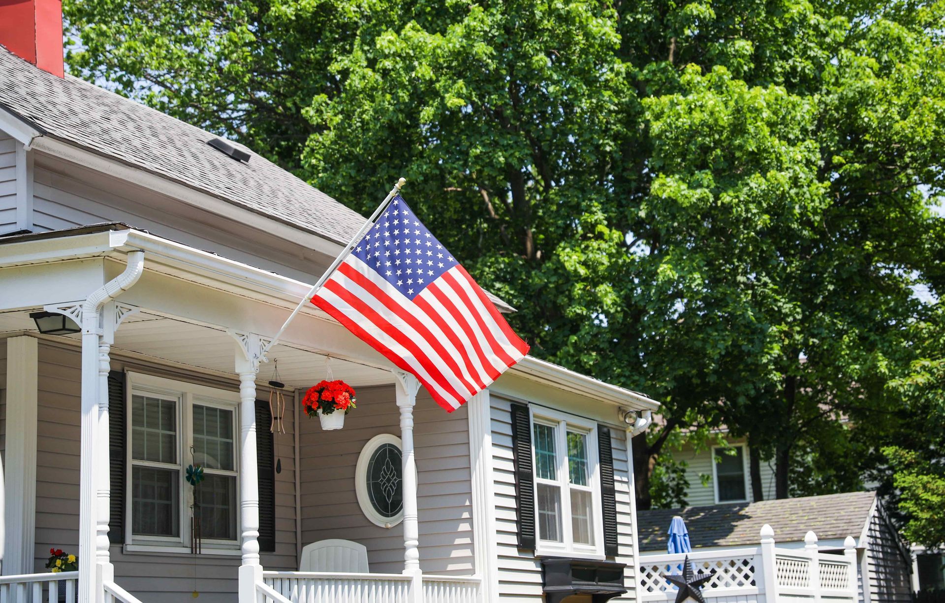 An american flag is flying on the porch of a house.