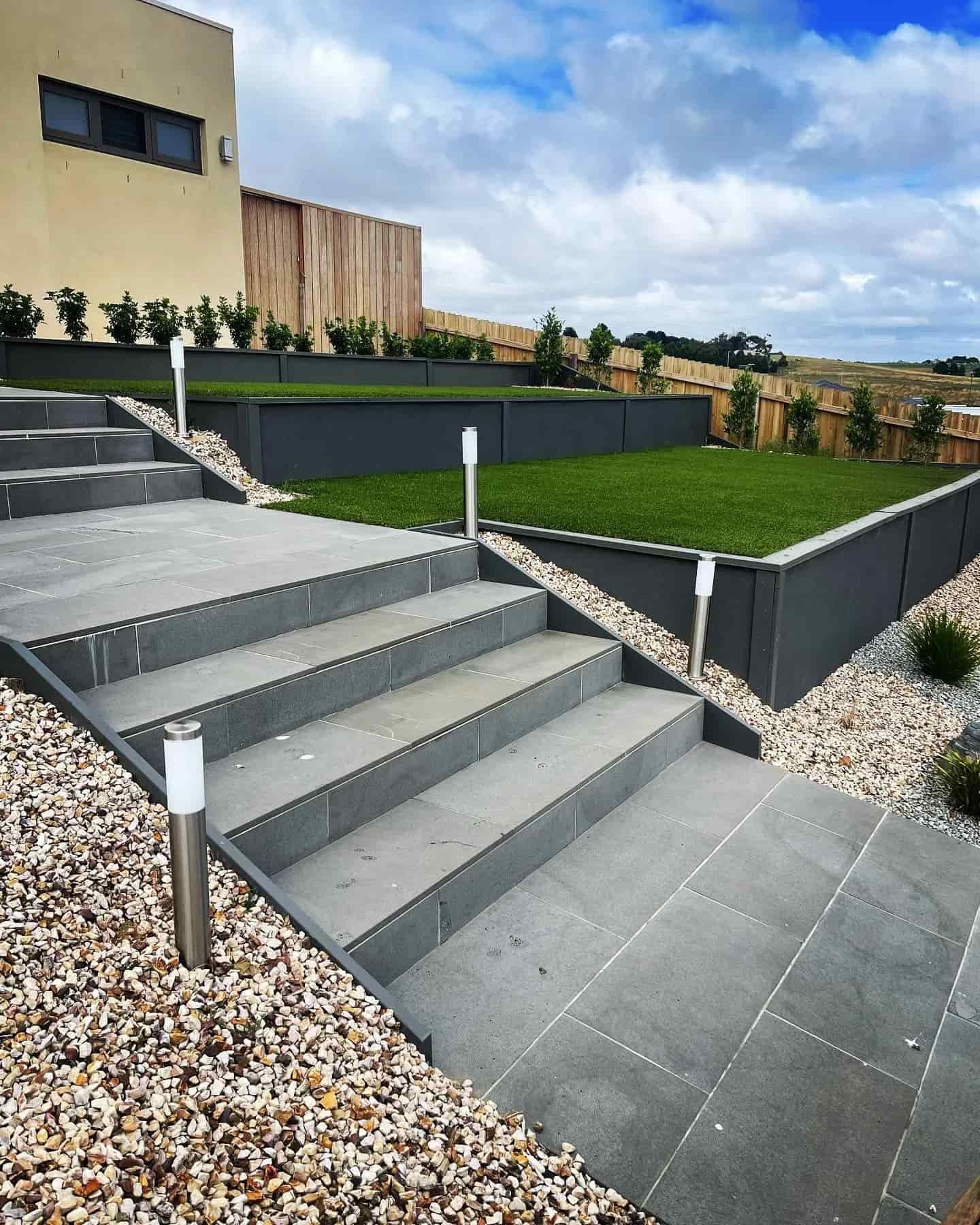 Stone steps leading up to a tiered, landscaped yard with grass and retaining walls — MGP Landscaping in Geelong, VIC 