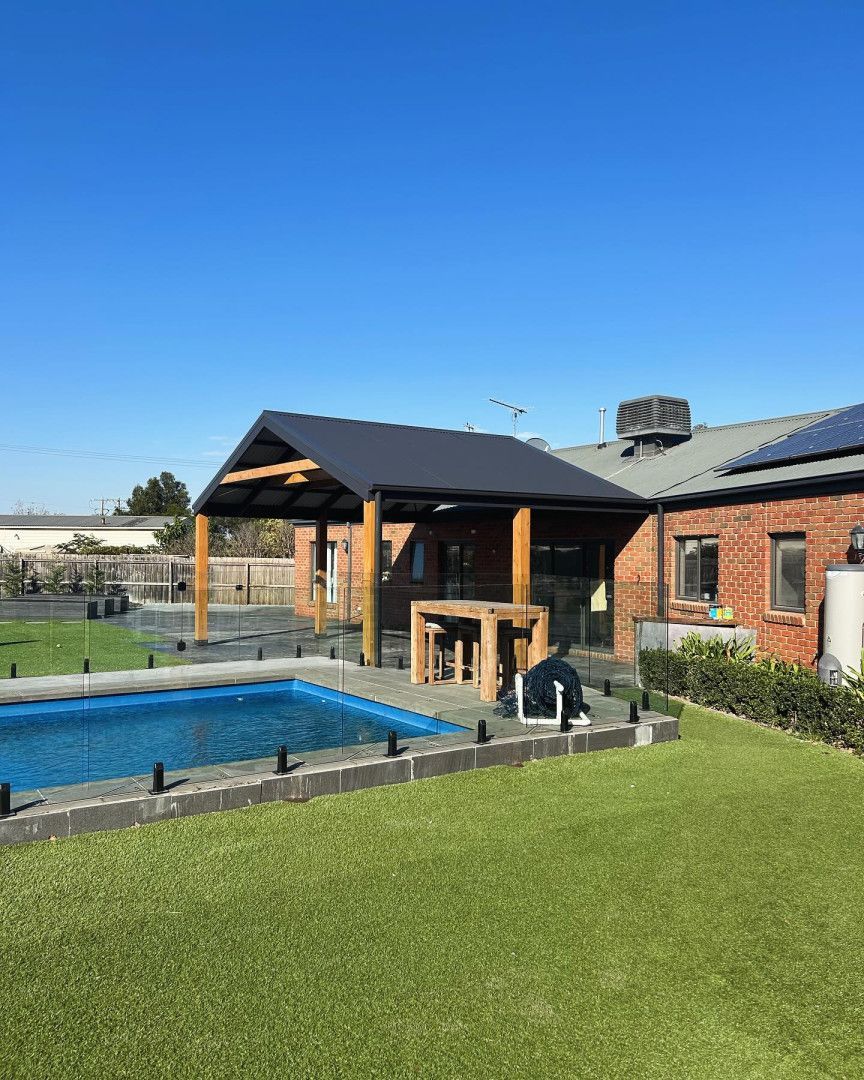 Backyard with pool, pergola, house with solar panels, and green lawn on a sunny day — MGP Landscaping in Geelong, VIC