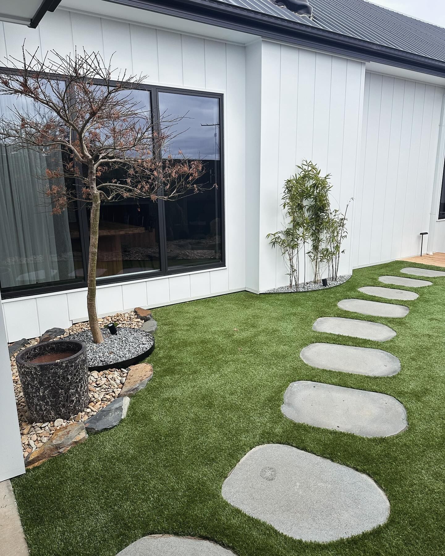 White house with black-framed window. Stone pathway through green lawn. Small trees and stone accents — MGP Landscaping in Geelong, VIC
