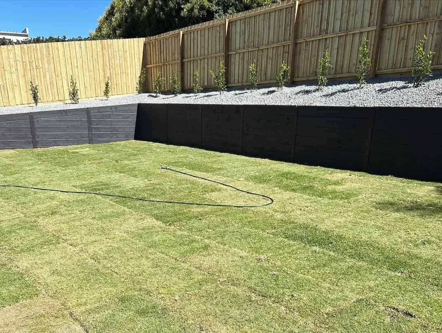 Lawn in a Backyard With a Retaining Wall, Gravel, and a Wooden Fence — MGP Landscaping in Geelong, VIC