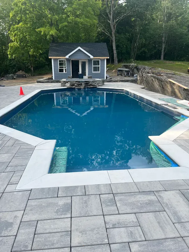 Woman in straw hat smiles, holding wine glass near a lake.