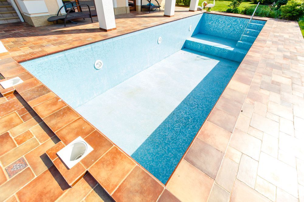 Woman in straw hat smiles, holding wine glass near a lake.