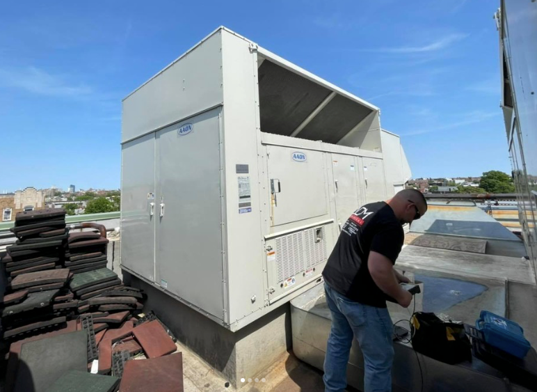 A man is installing an air conditioner on the side of a house.