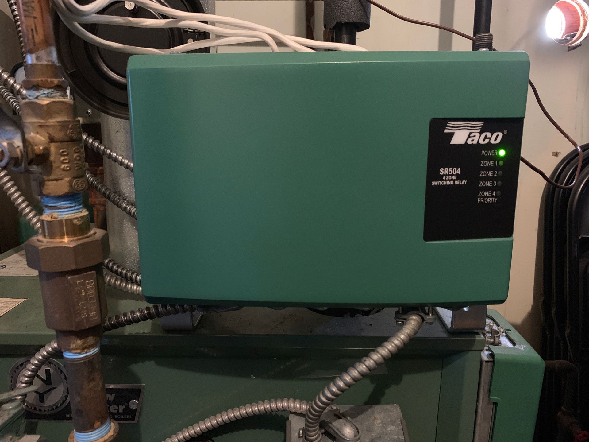 A green box is sitting on top of a green boiler.