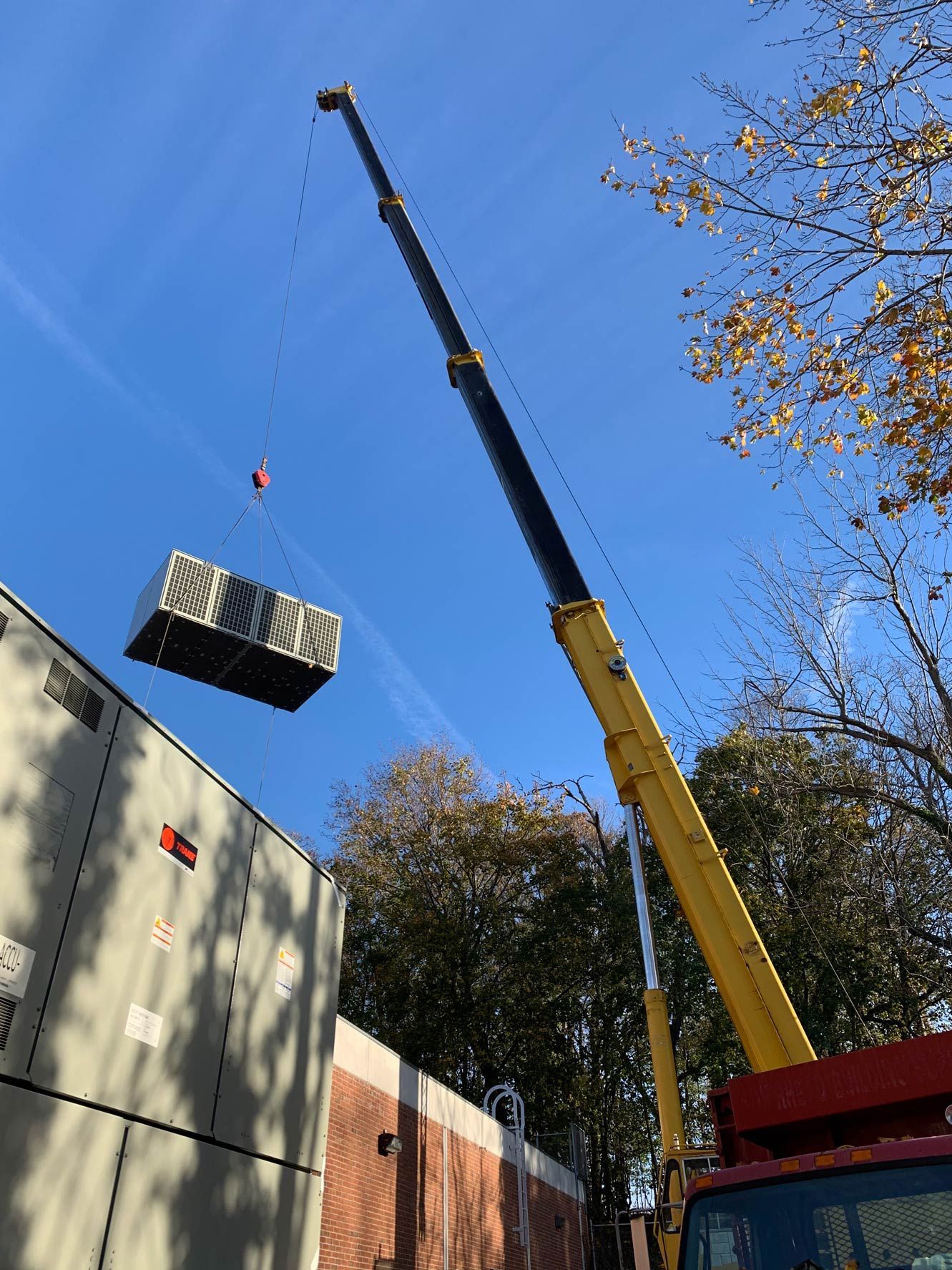 A yellow crane is lifting a container into the air