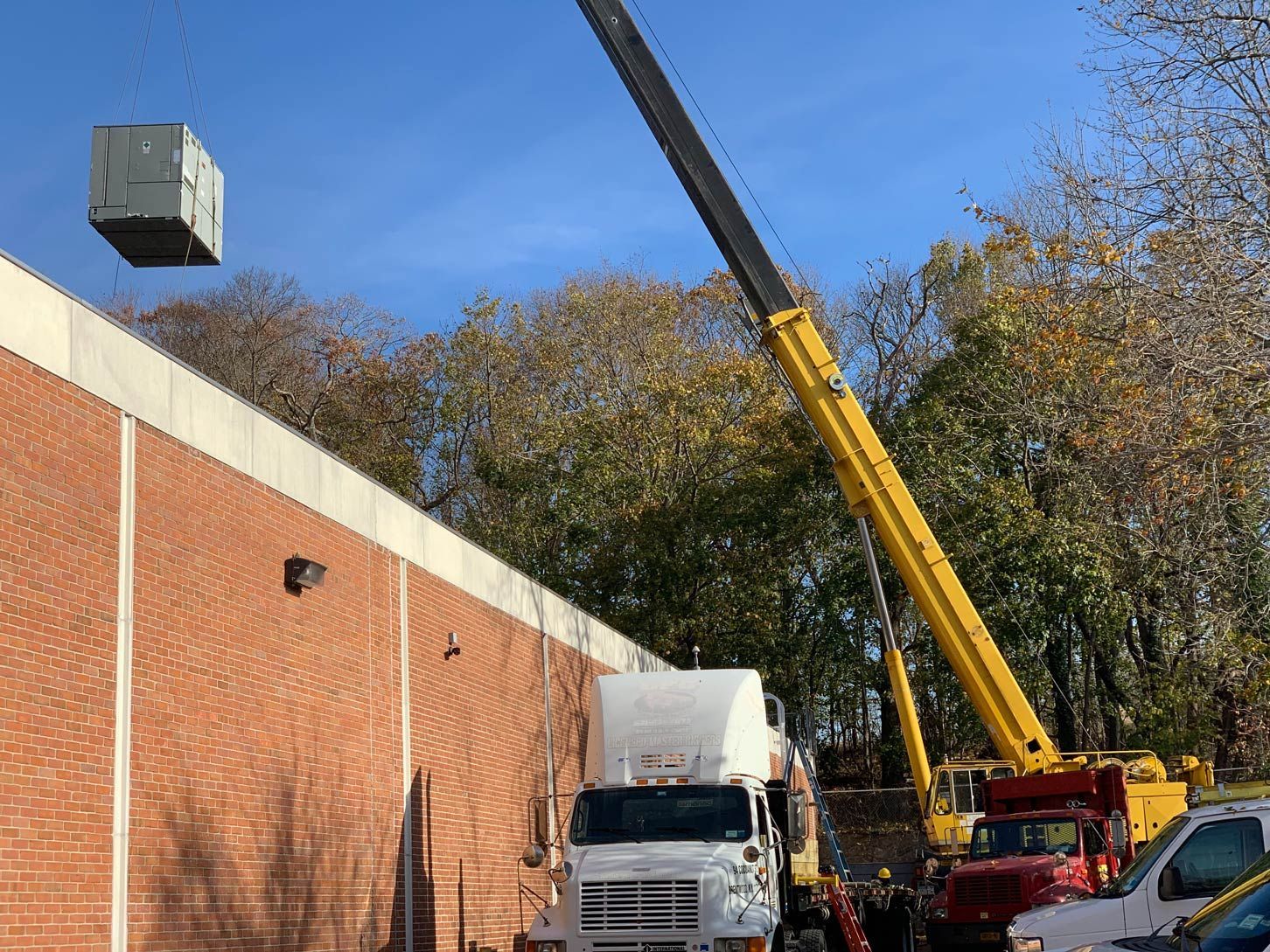 A crane is lifting a box from the roof of a building.