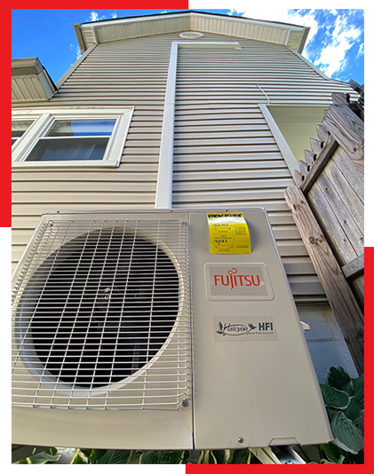 A fujitsu air conditioner is mounted on the side of a house.