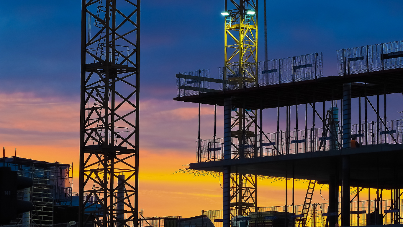 Two construction workers are standing in front of a building under construction.