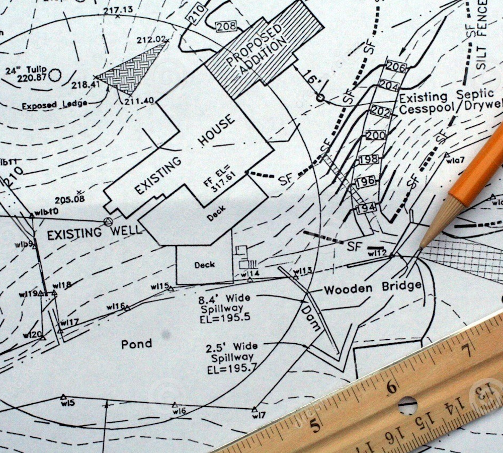 A man is standing on the side of a road using a theodolite.