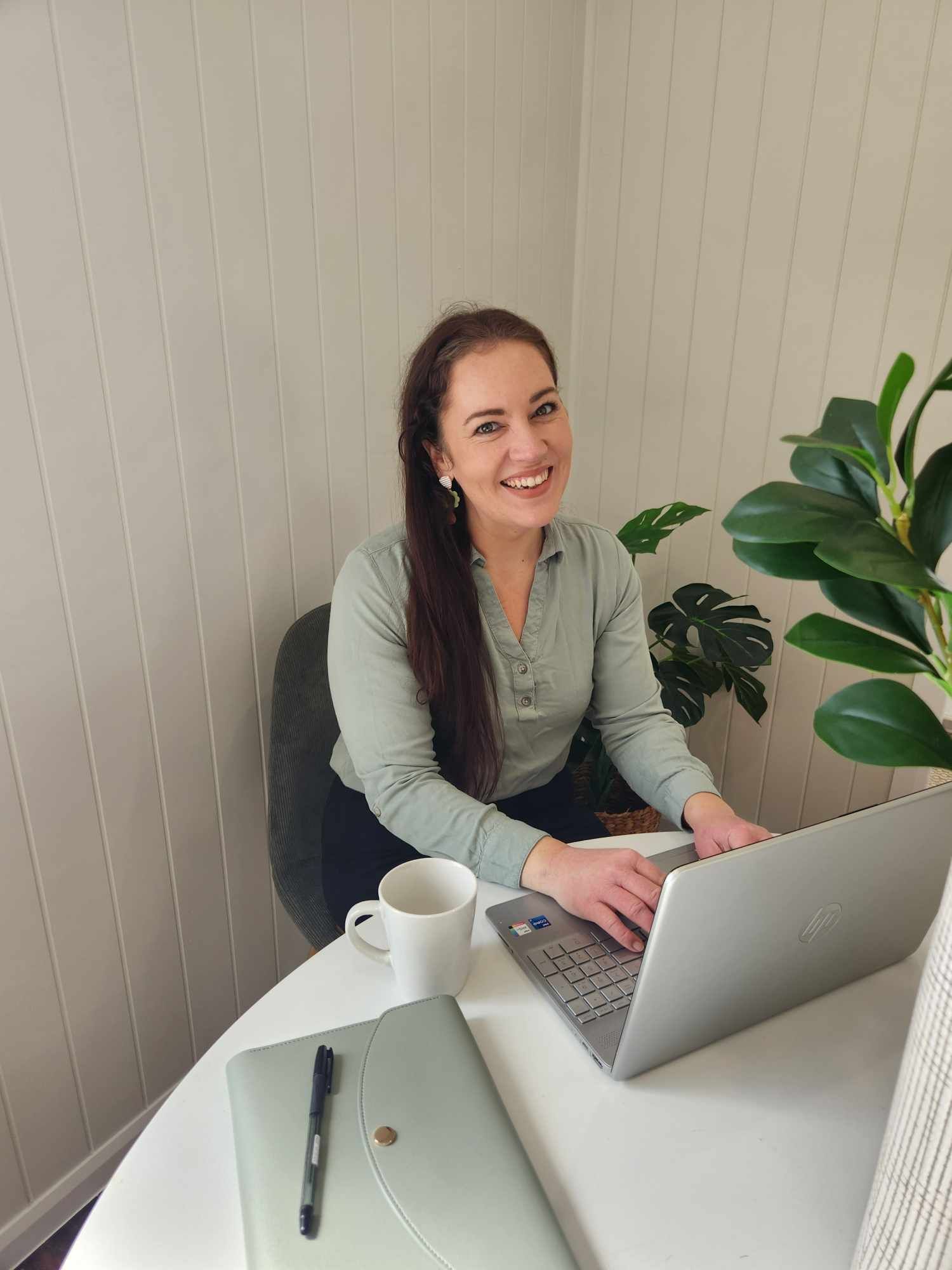 A woman is sitting at a table using a laptop computer Emmel Finance in Townsville, QLD
