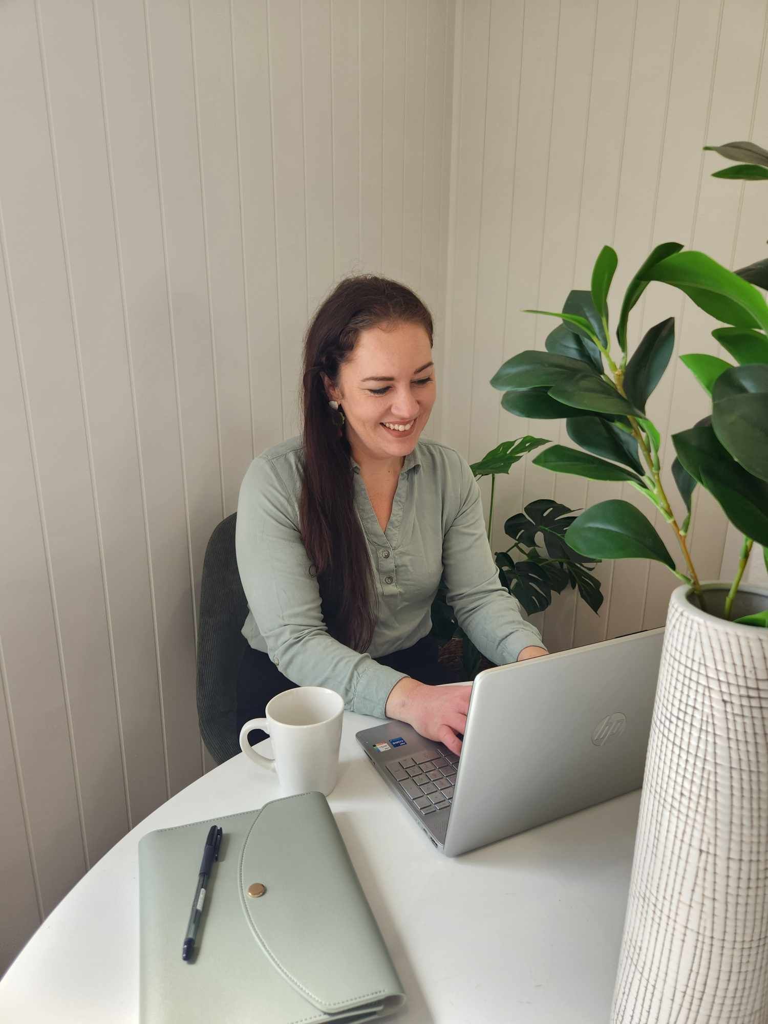 A Woman Is Sitting At A Table Using A Laptop Computer — Emmel Finance in Townsville, QLD