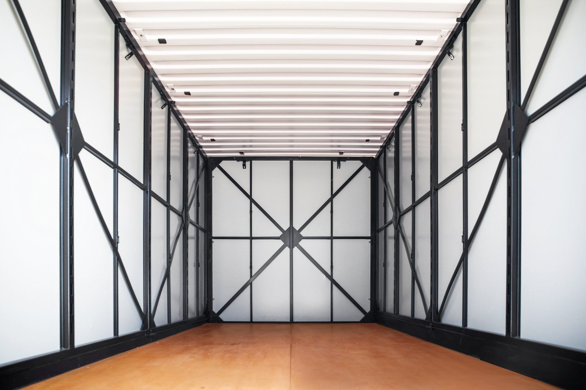 An empty shipping container with a wooden floor and white walls.