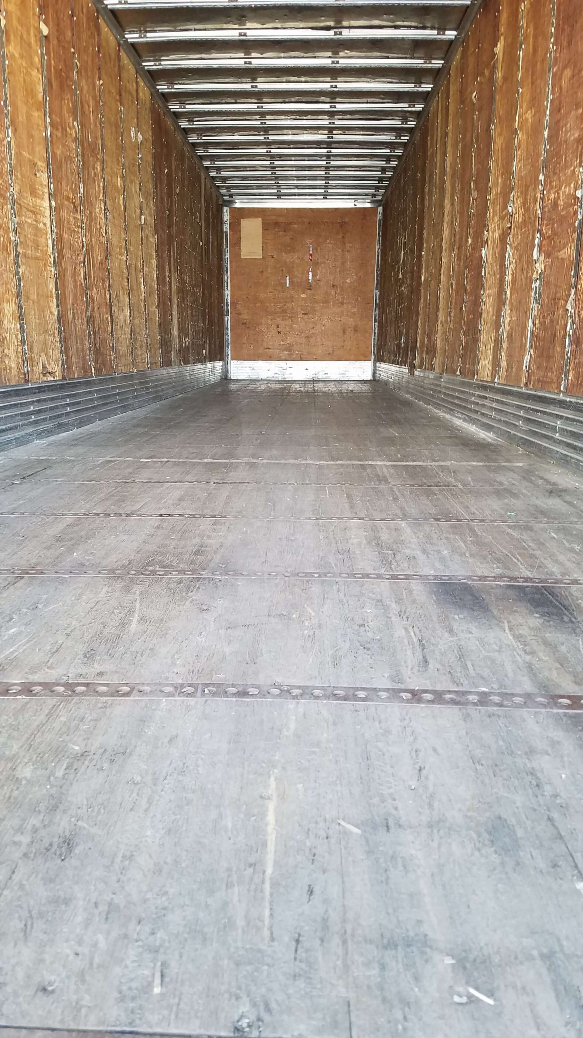 The inside of an empty trailer with the door open.