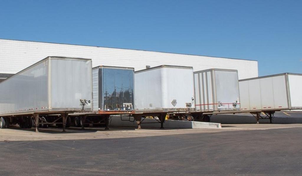 A row of semi trucks parked in front of a warehouse.