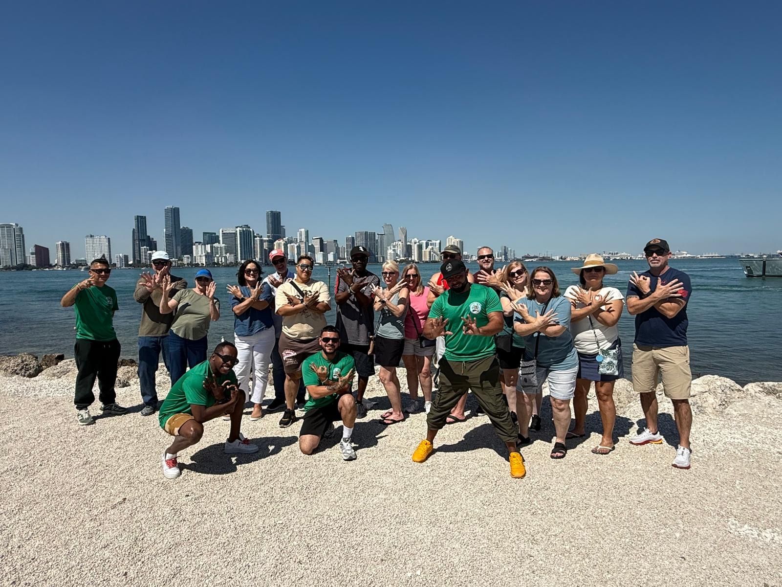 Guest posing with the tour guide and driver at the final stop of the Miami hop on hop off tour, with the secret Miami skyline view in the background.
