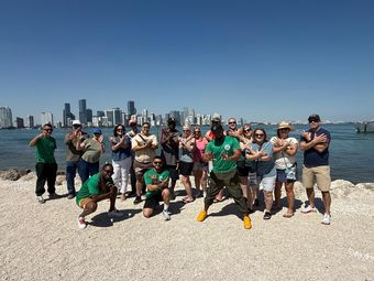 Guest posing with the tour guide and driver at the final stop of the Miami hop on hop off tour, with the secret Miami skyline view in the background.
