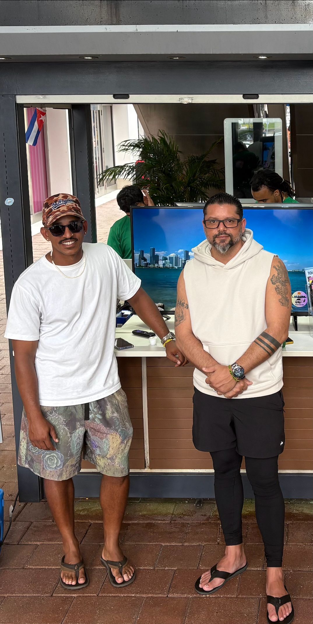 Randy and Junior in 2025 — founders of Hop On Hop Off Miami standing at their Bayside Marketplace kiosk, continuing to redefine Miami sightseeing with their modern city tour experience.