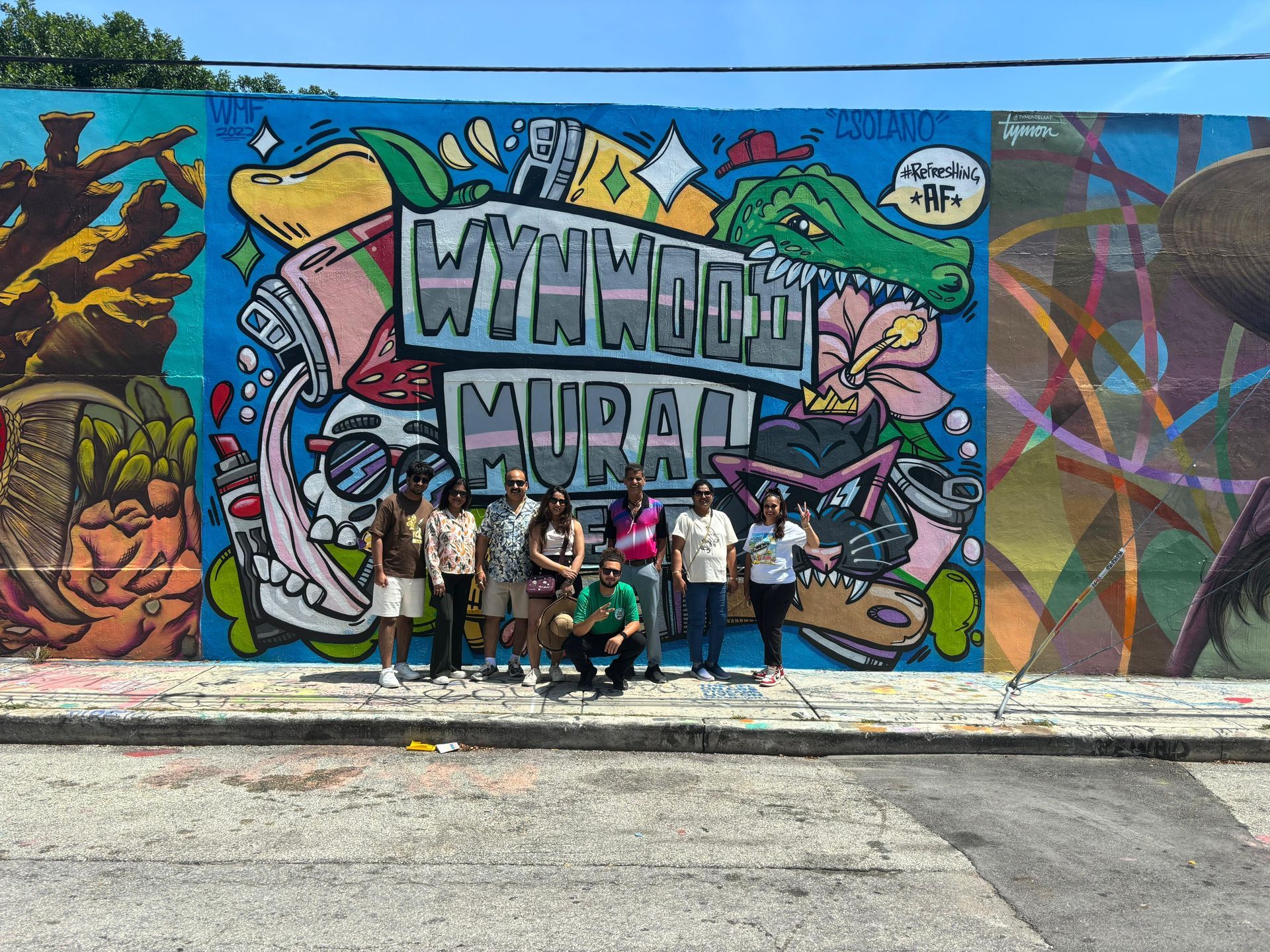 Group photo in Wynwood Walls with colorful mural in the back on the Miami Hop on Hop off Bus