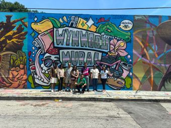 Group photo in Wynwood Walls with colorful mural in the back on the Miami Hop on Hop off Bus