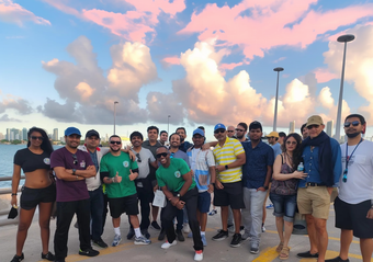 Full Hop on Hop off Miami tour bus with passengers gathered outside taking photos with the tour guide and driver at Bayside Marketplace in