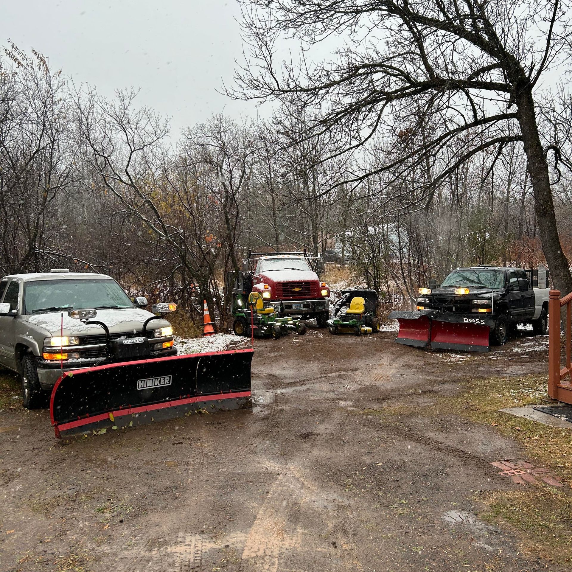 A group of snow plows are parked in a parking lot.
