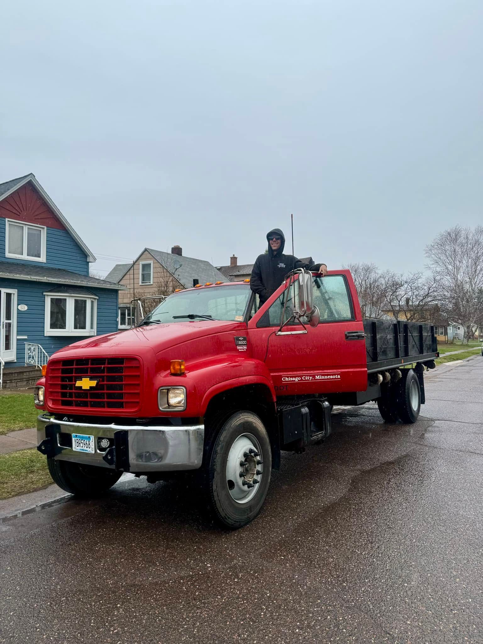 A man is standing in the back of a red truck.
