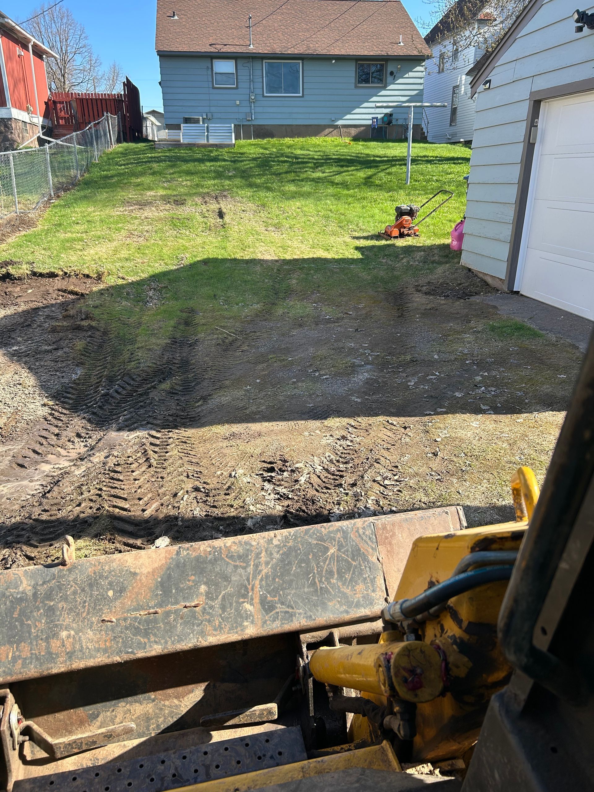 A bulldozer is moving dirt in front of a house.