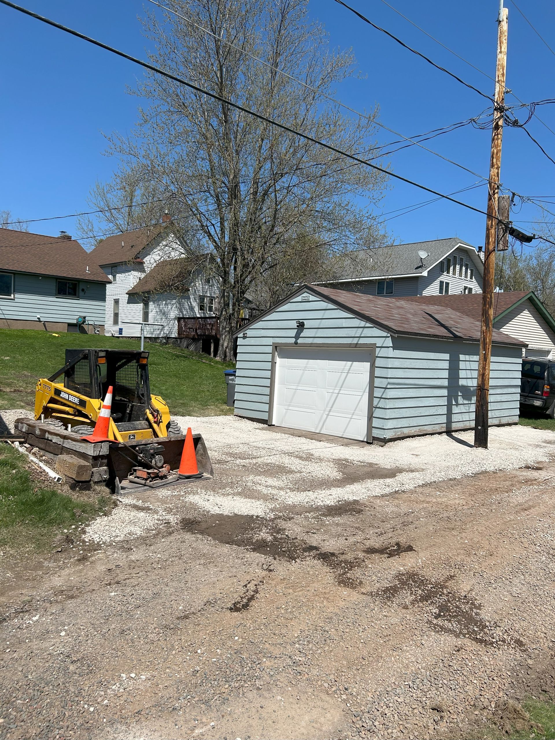 A bulldozer is parked on the side of the road in front of a garage.