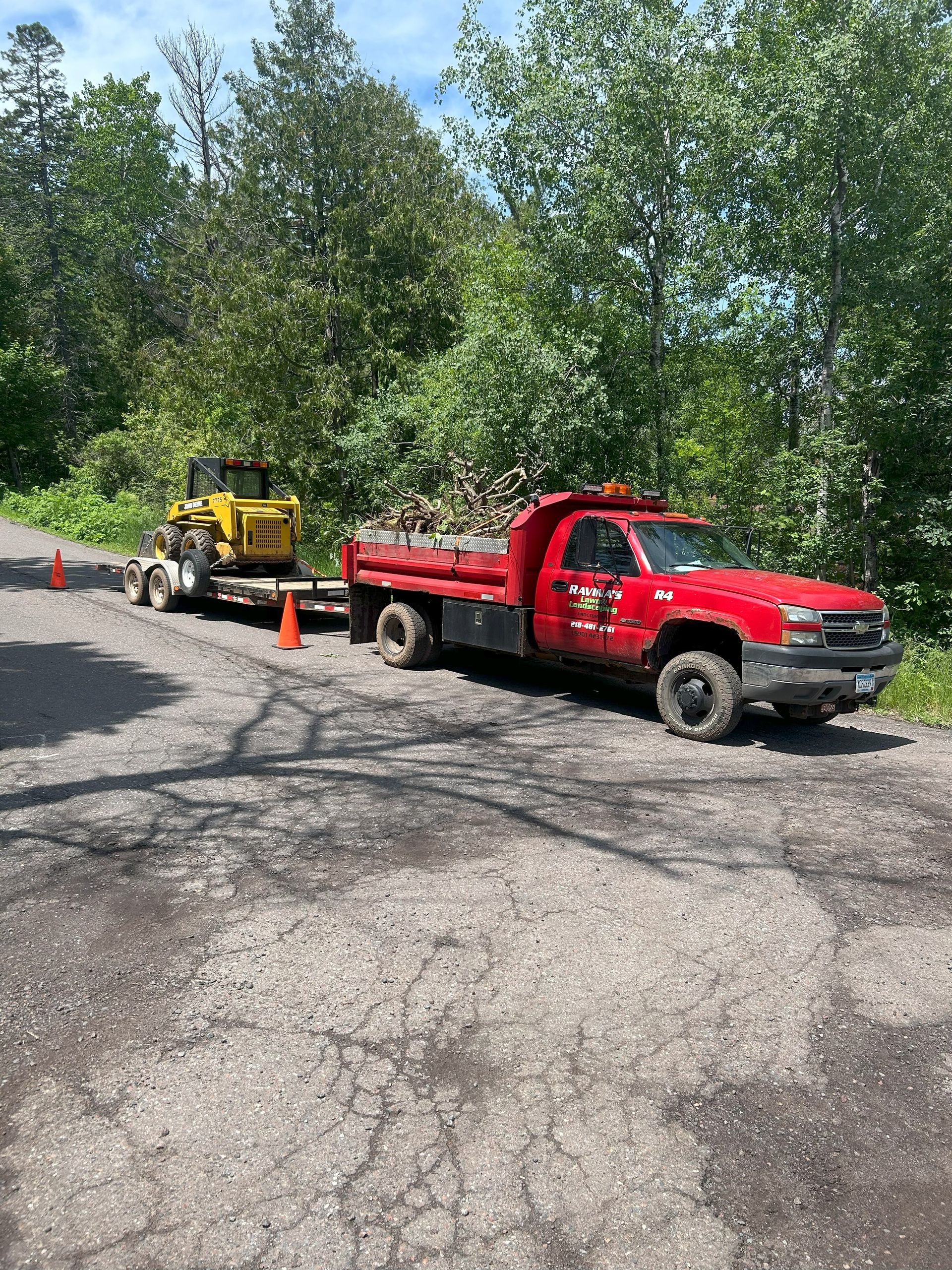 A red truck is towing a yellow bulldozer down a road.