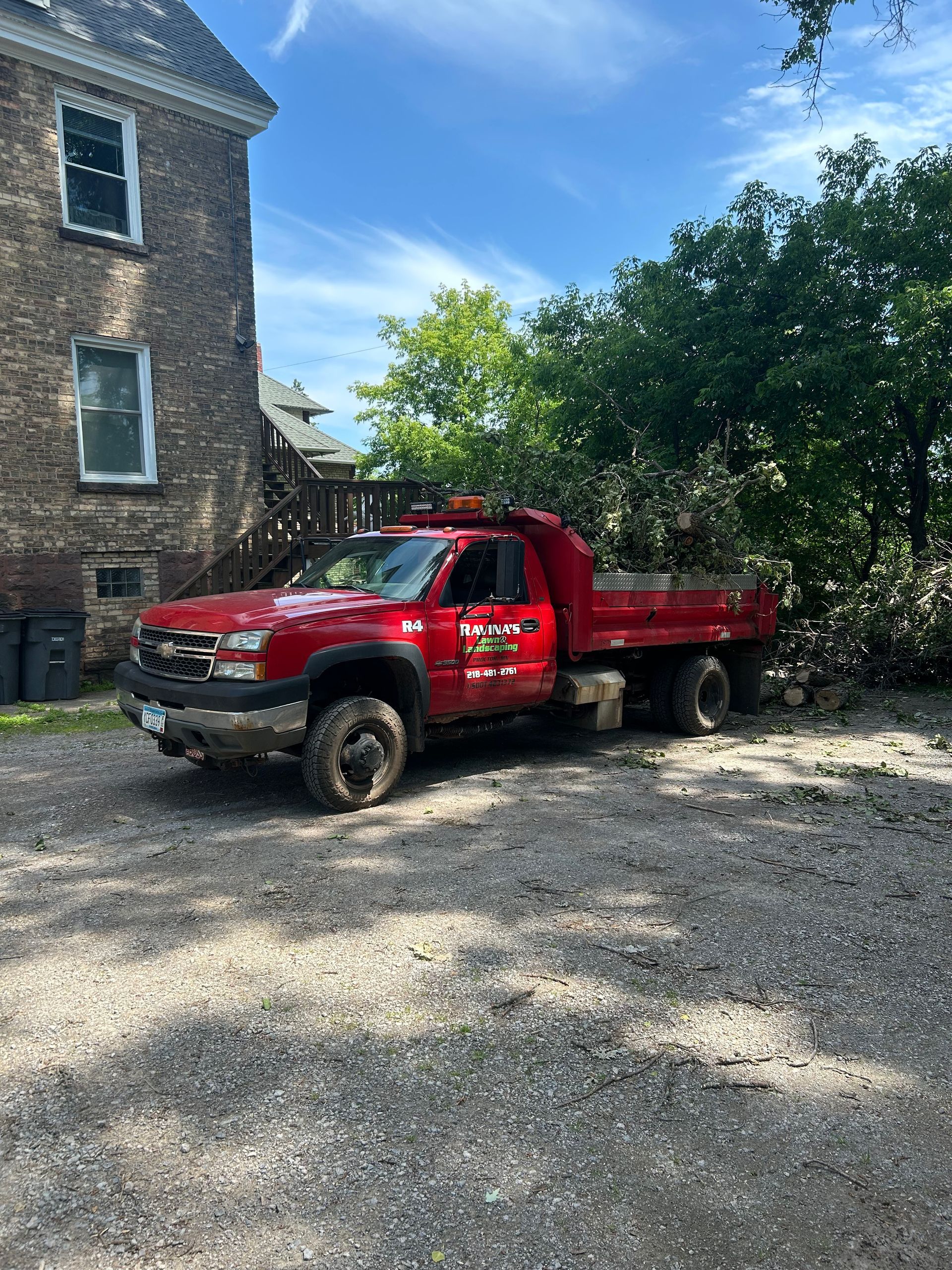 A red dump truck is parked in front of a brick building.