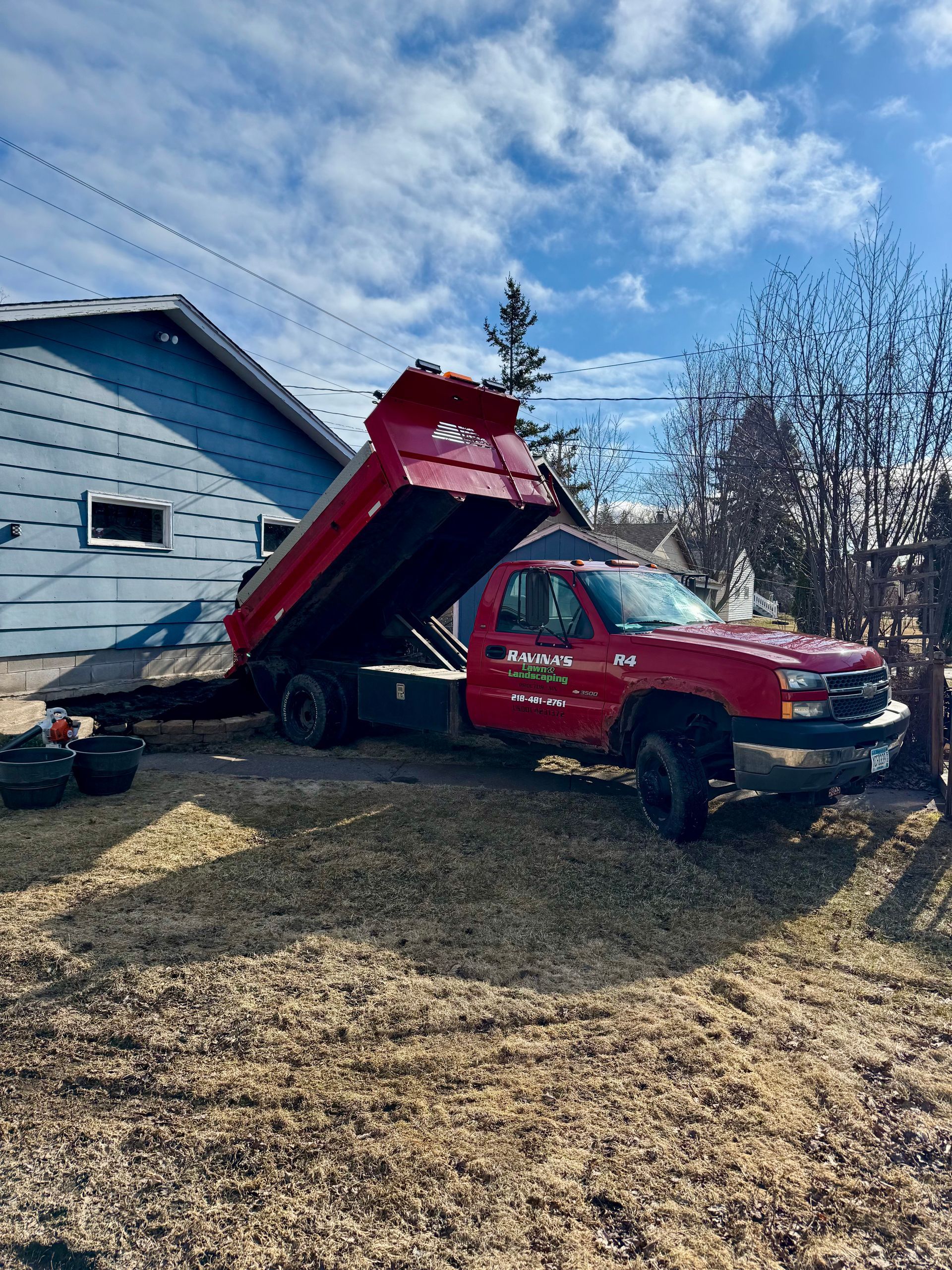 A red dump truck is parked in front of a house.