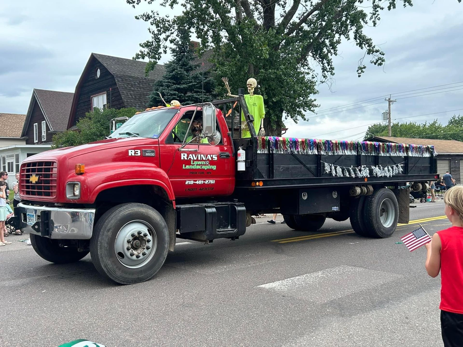 A red truck is driving down the street in a parade.