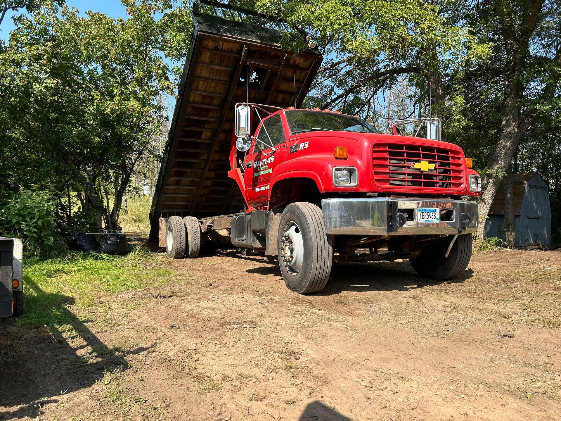 A red dump truck is parked in a dirt lot.