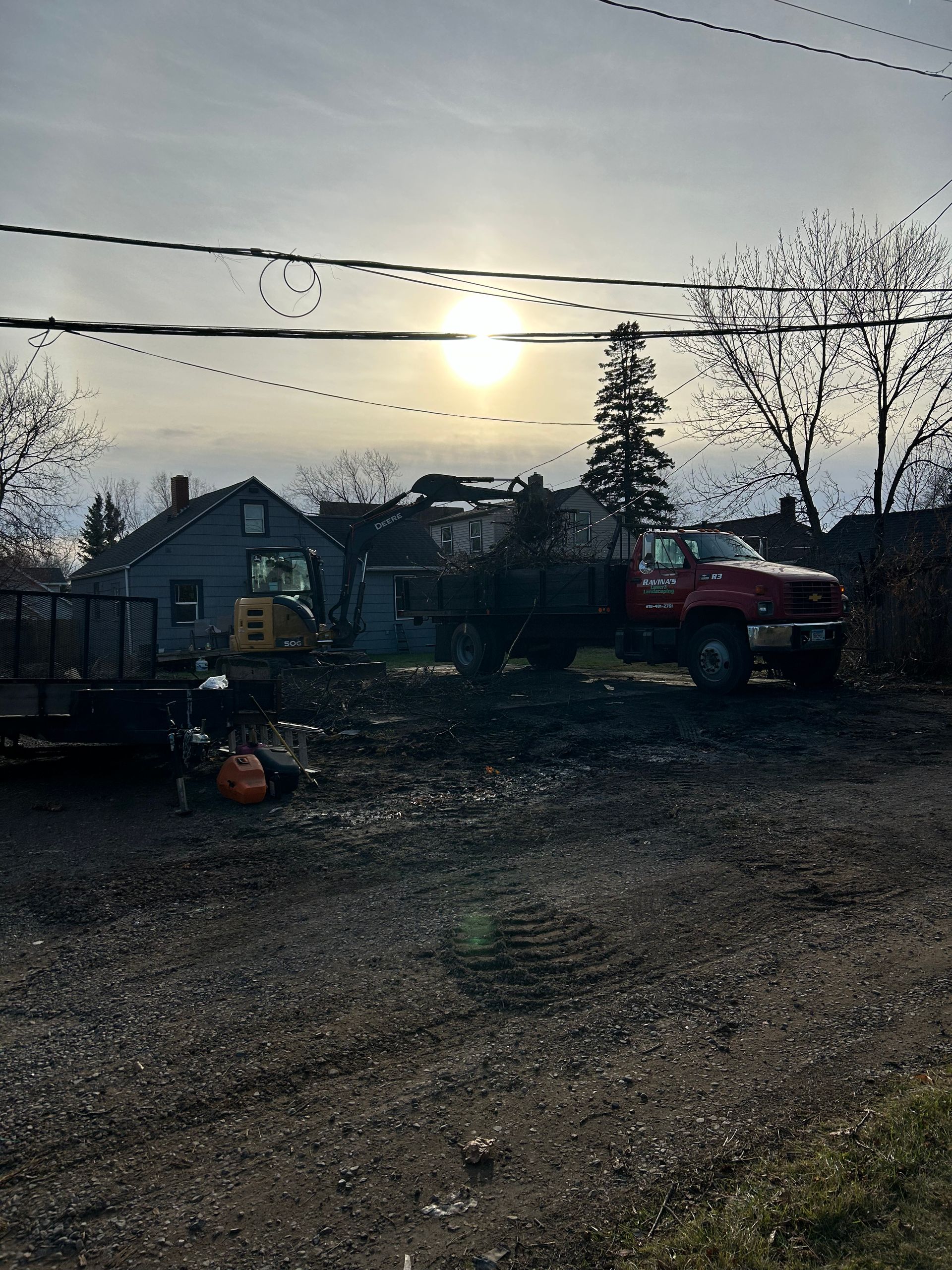 A red truck is parked in a dirt lot in front of a house.