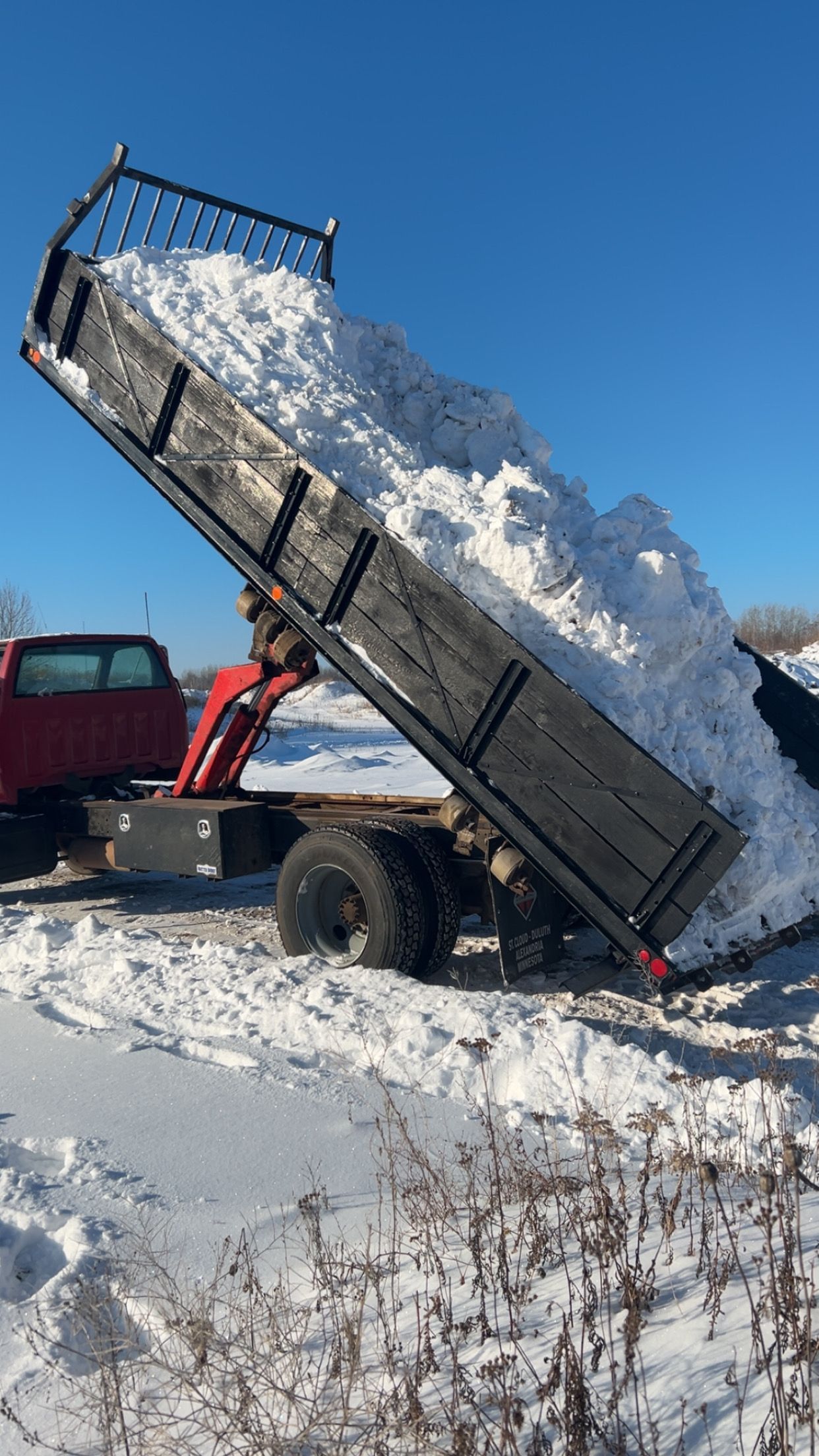 A dump truck is being loaded with snow on a snowy road.